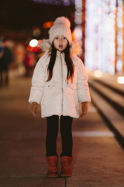 Schattig bang verloren klein meisje in een grote stad in de avond in de winter