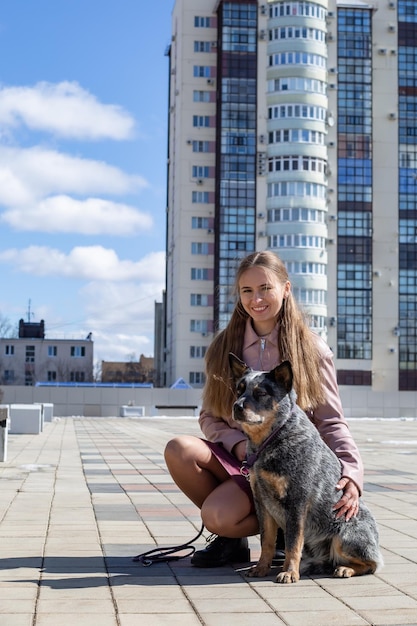 schattig blond meisje knuffelt een genezerrashond in de stad