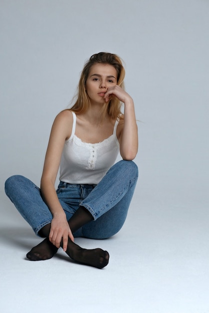 Schattig blond model draagt een casual outfit die poseert op de grijze studio-achtergrond