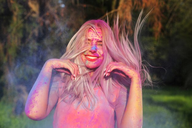 Schattig blond model met fladderend haar poseren bedekt met een kleurrijke verf op het Holi Festival