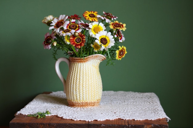 Schattig boeket bloemen in een kruik op een groene achtergrond