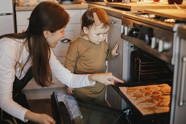 Schattig dochtertje en moeder kerst peperkoek koekjes bakken in moderne scandinavische keuken