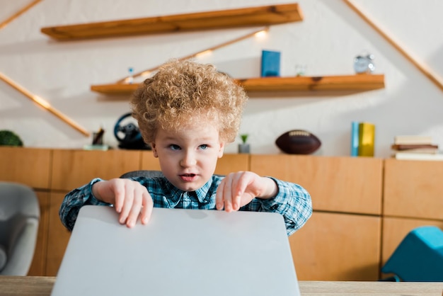 Schattig en slim kind dat laptop aanraakt terwijl het thuis studeert