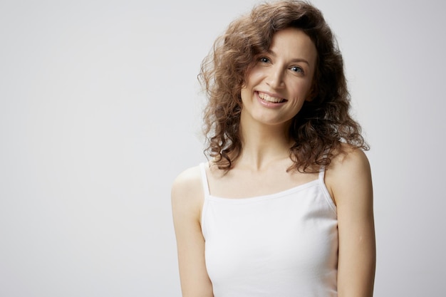 Schattig gelukkig genoten krullend mooie vrouw in basic witte tshirt glimlacht op camera poseren geïsoleerd op over witte achtergrond mensen emoties Lifestyle concept kopie ruimte