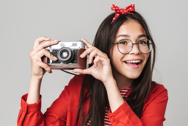 Schattig gelukkig tienermeisje met een casual outfit die geïsoleerd over een grijze muur staat en foto's maakt met een portretcamera