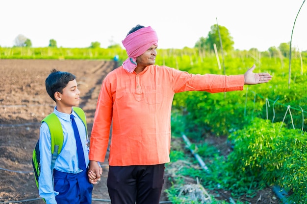 Schattig indisch boerenkind in schooluniform met zijn vader op landbouwgebied