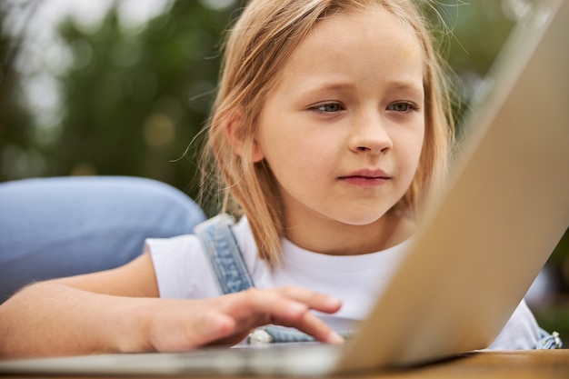 schattig jong meisje dat naar de schermcomputer kijkt terwijl ze op internet surft in het stadspark