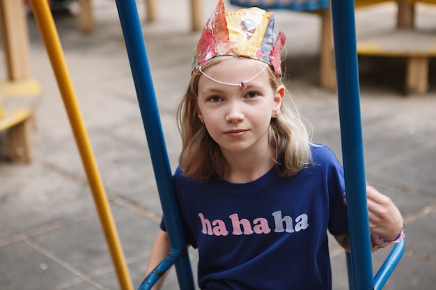 Schattig jong meisje geniet van spelen op schommel op playgorund in het park