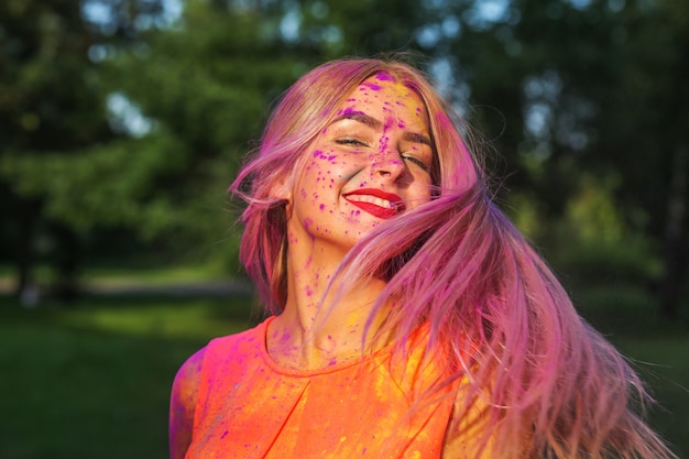 Schattig Kaukasisch model met haar in beweging spelend met kleurrijke droge verf op het Holi Festival
