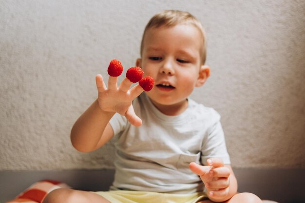 schattig kind frambozen eten op een grijze achtergrond