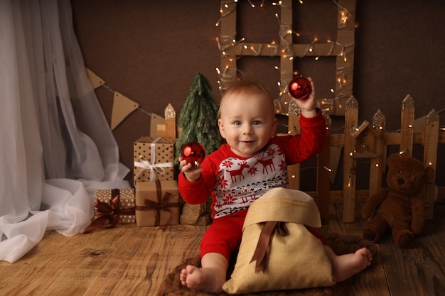 Schattig kind in nieuwjaarspyjama haalt kerstballen uit een tas met cadeaus