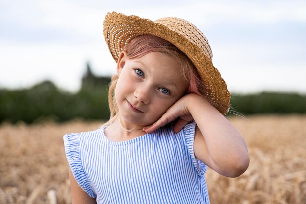 Schattig kind klein meisje in een hoed op een achtergrond van een tarweveld