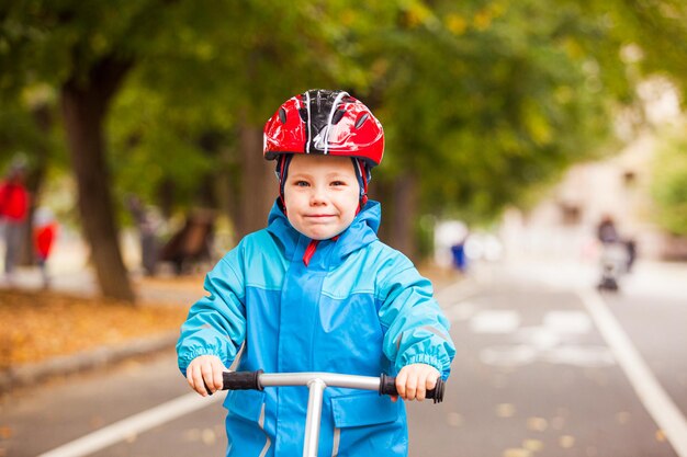 Schattig kind van drie jaar portret in helm. Jongen rijdt op loopfiets op fietspad in herfstpark