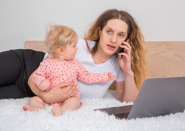 Schattig klein babymeisje met laptop in ouder slaapkamer