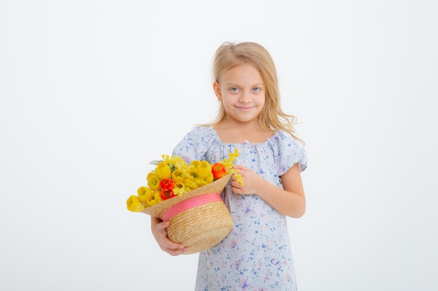 Schattig klein blond meisje in een bedrijf een boeket van Lentebloemen op een witte achtergrond