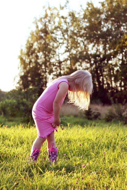 Schattig klein blond meisje in een weide in zonnige zomerdag