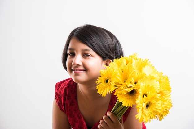Schattig klein Indiaas meisje met een bos of boeket verse gele Gerbera-bloemen. Geïsoleerd op witte achtergrond