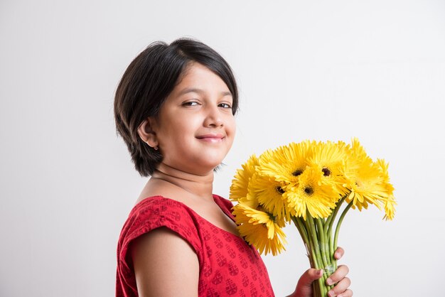 Schattig klein Indiaas meisje met een bos of boeket verse gele Gerbera-bloemen. Geïsoleerd op witte achtergrond