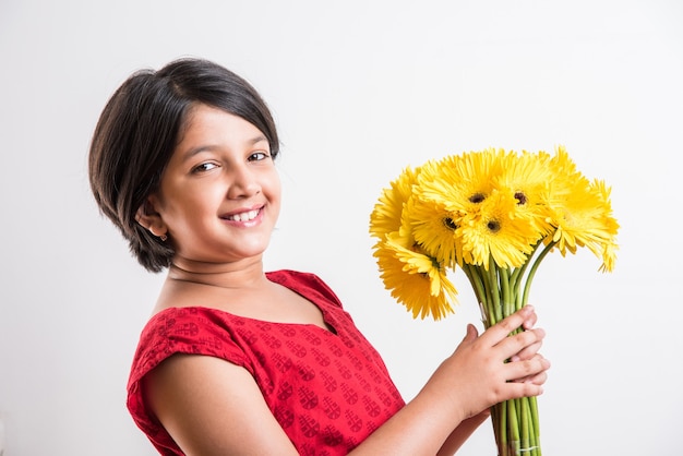 Schattig klein Indiaas meisje met een bos of boeket verse gele Gerbera-bloemen. Geïsoleerd op witte achtergrond