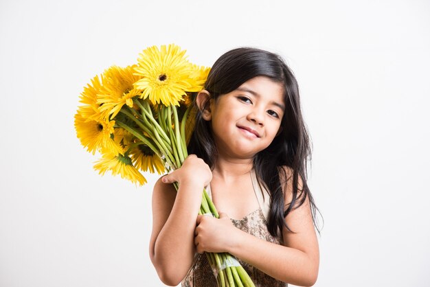 Schattig klein indiaas meisje met een bos of boeket verse gele gerbera-bloemen. geïsoleerd op witte achtergrond