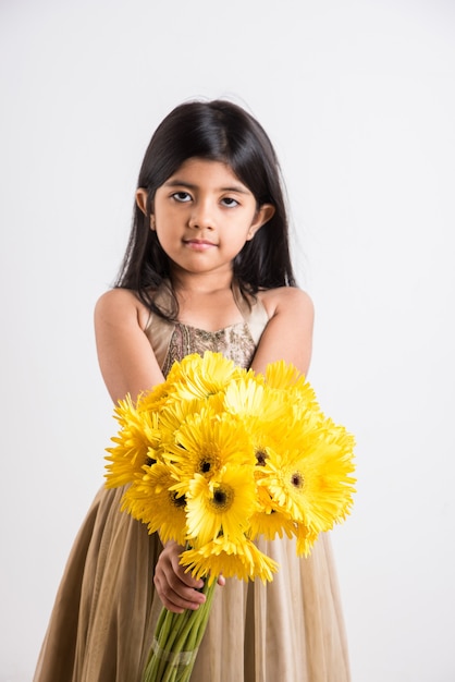 Schattig klein Indiaas meisje met een bos of boeket verse gele Gerbera-bloemen. Geïsoleerd op witte achtergrond