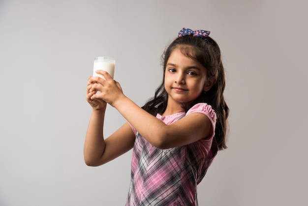 Schattig klein Indiaas of Aziatisch meisje met een glas melk - gezond eetconcept