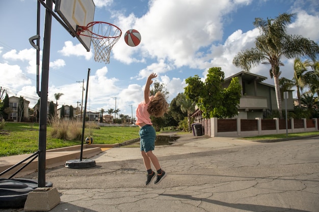 Schattig klein jongenskind dat met basketbal springt voor geschoten schattig kind dat basketbal speelt