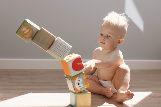 Schattig klein jongenskind dat thuis speelt met kleurrijke kubussen