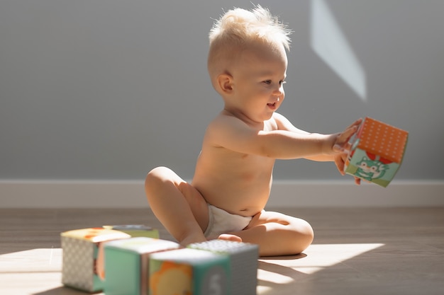 Foto schattig klein jongenskind dat thuis speelt met kleurrijke kubussen