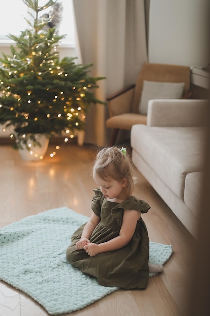 Schattig klein kind meisje en de kerstboom binnenshuis Prettige Kerstdagen en Gelukkig Nieuwjaar concept