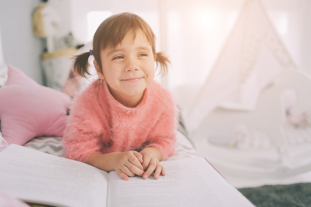 Schattig klein kind meisje leest thuis een boek. grappig mooi kind plezier in kinderkamer.