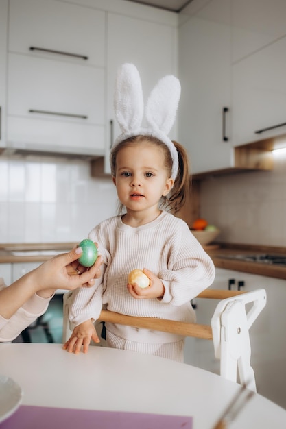 Schattig klein kind met bunny oren Meisje zittend op het raam met het schilderen van eieren