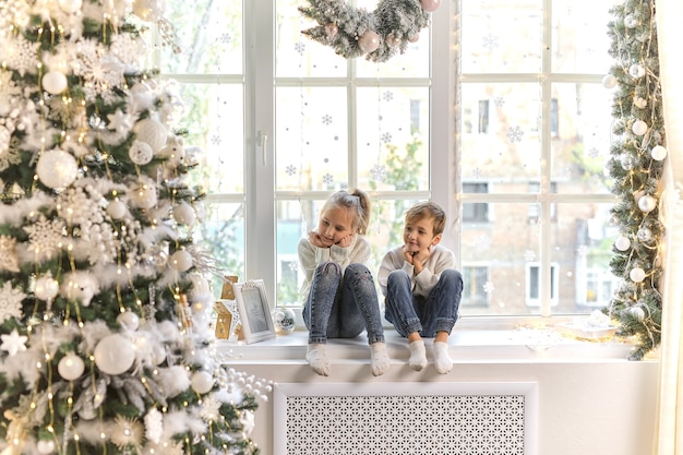 Schattig klein kind op de vensterbank thuis wachten op kerstviering