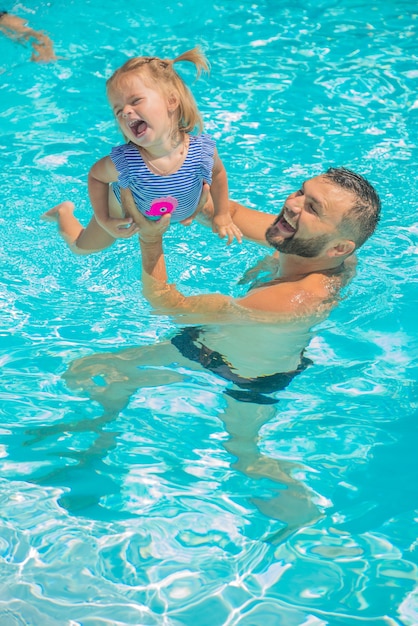 schattig klein kind spelen in het zwembadwater met papa