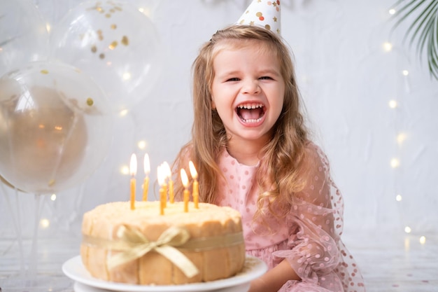 Schattig klein kindmeisje blaast kaarsen op verjaardagstaart en viert verjaardag