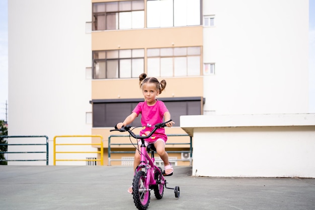 Schattig klein lachend meisje fiets fiets in de stad op zonnige zomerdag parkeren actieve familie vrije tijd met kinderen