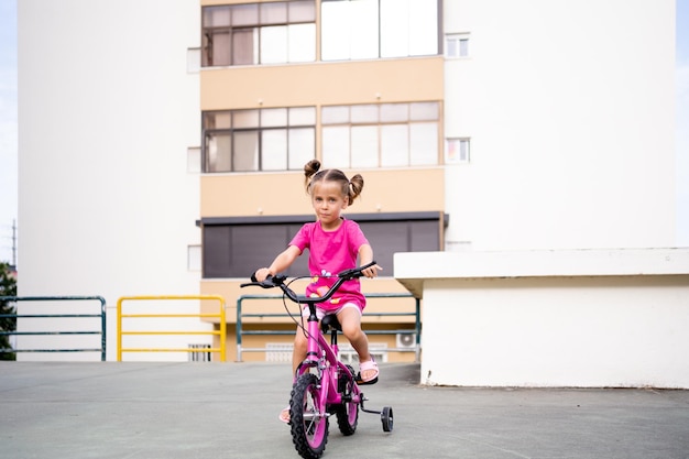 Schattig klein lachend meisje fiets fiets in de stad op zonnige zomerdag parkeren Actieve familie vrije tijd met kinderen