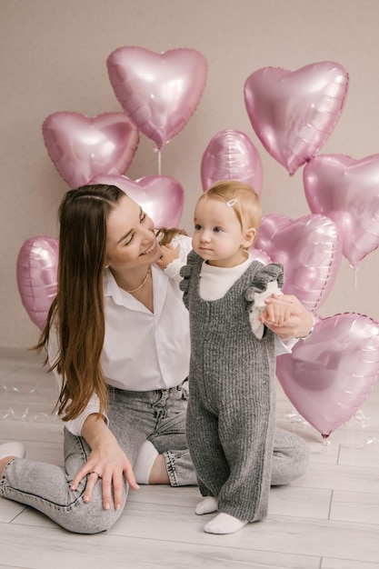 Schattig klein meisje 1e verjaardag baby met moeder en roze ballon harten ballon foto zone