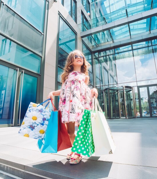 Schattig klein meisje bij het winkelen. Portret van een kind met boodschappentassen. Boodschappen doen. meisje.