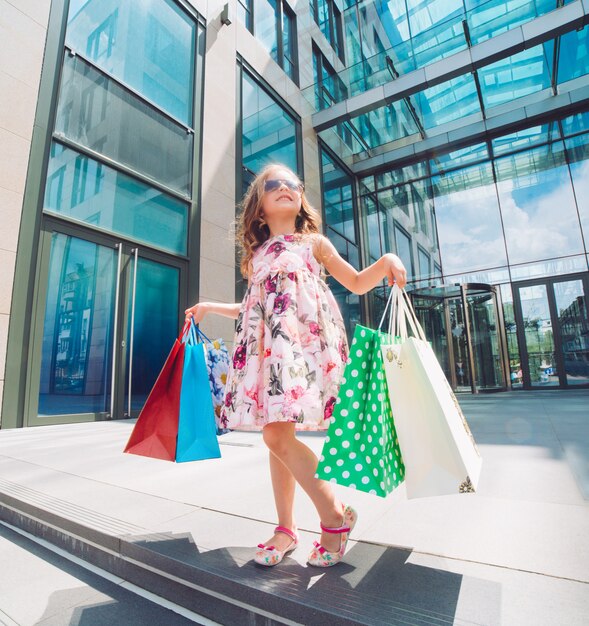 Schattig klein meisje bij het winkelen. Portret van een kind met boodschappentassen. Boodschappen doen. meisje.