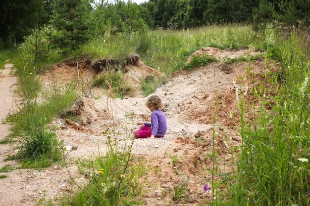 Schattig klein meisje buiten spelen met zand in de zomer op het platteland