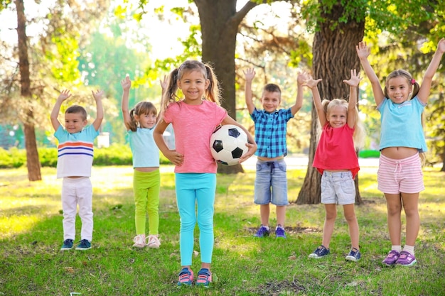 Schattig klein meisje dat balspel speelt met andere kinderen in het park