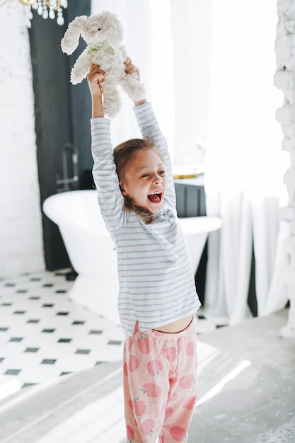 Schattig klein meisje dat plezier heeft met speelgoed in de heldere badkamer thuis