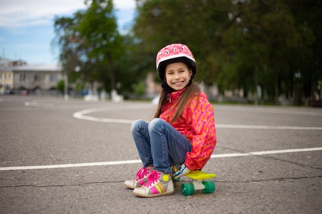 Schattig klein meisje dragen helm rijden op een skateboard in mooie zomerse park