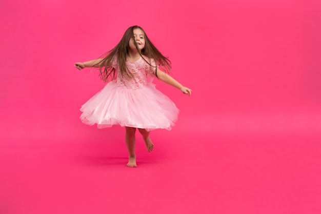 Schattig klein meisje droomt ervan ballerina te worden. Klein dansend meisje. Studio Schieten Over Roze Achtergrond.