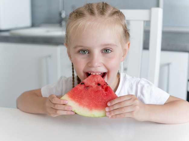 Schattig klein meisje eet een watermeloen in de keuken