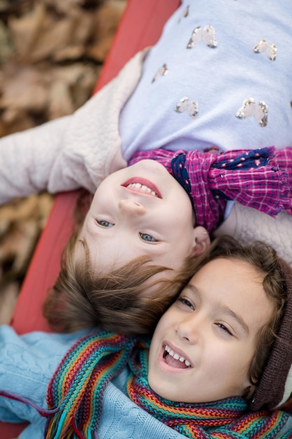 schattig klein meisje en jongen in kinderpark met plezier en vreugde tijdens het spelen in de speeltuin op een bewolkte herfstdag