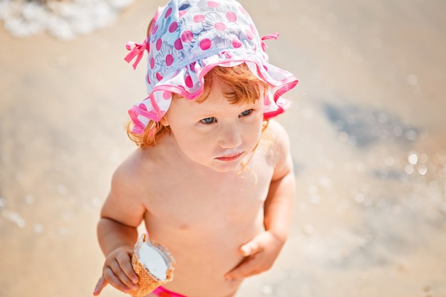 Schattig klein meisje eten van ijs op strandvakantie