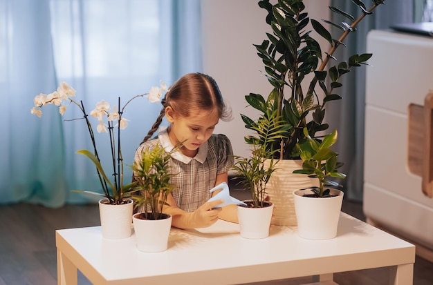 Schattig klein meisje geeft de plant in de potten thuis water, concept van plant groeiende leeractiviteit voor voorschoolse kinderen