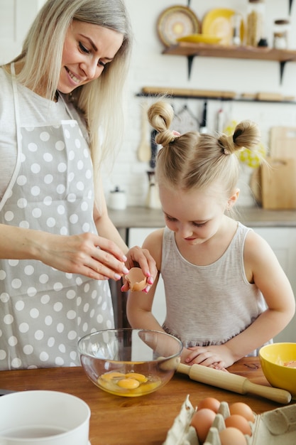 Schattig klein meisje helpt moeder koekjes te bakken in de keuken. Gelukkig gezin. Tonen.